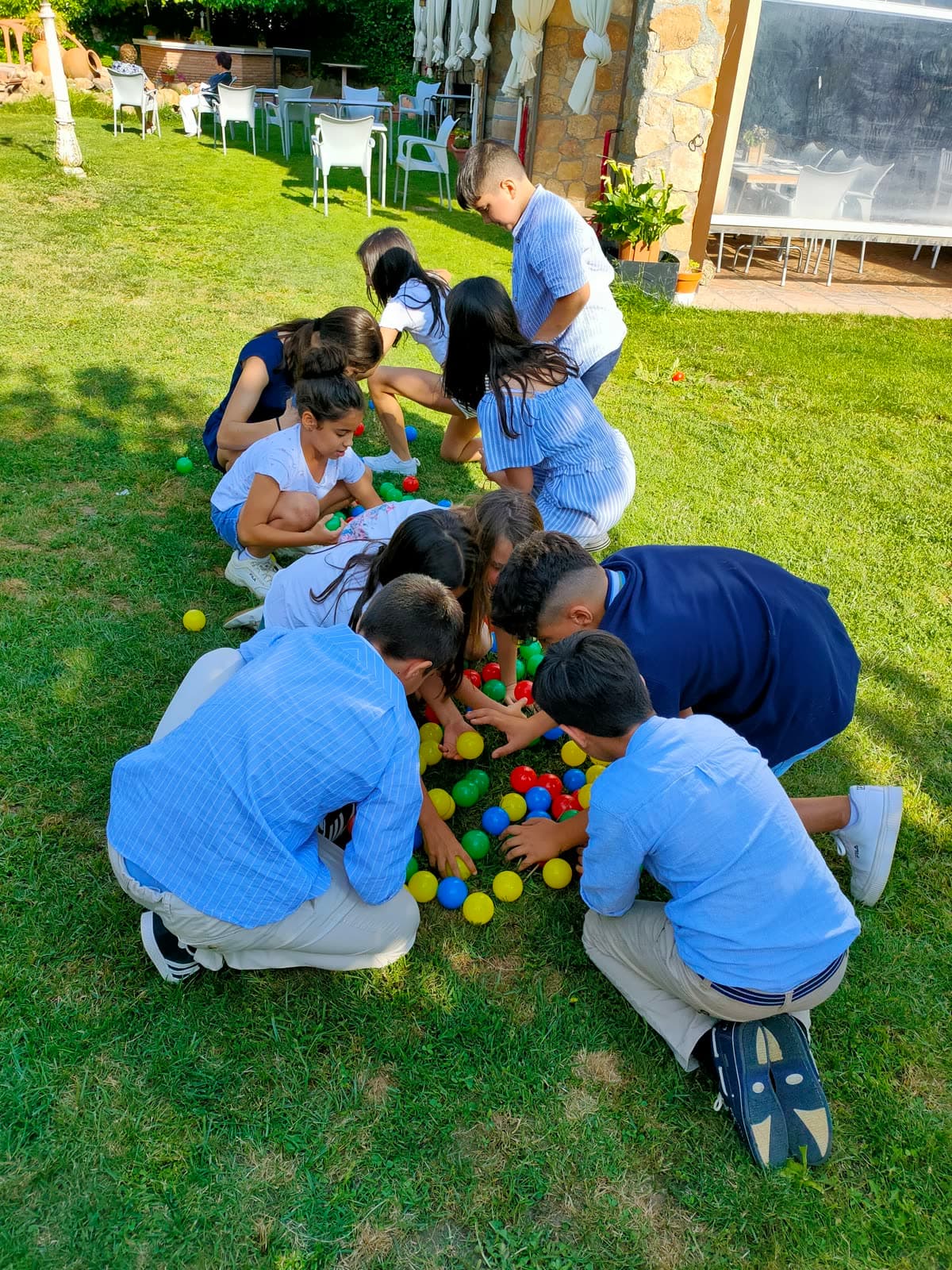 Grupo de niños jugando con pelotas de colores en el césped durante una celebración