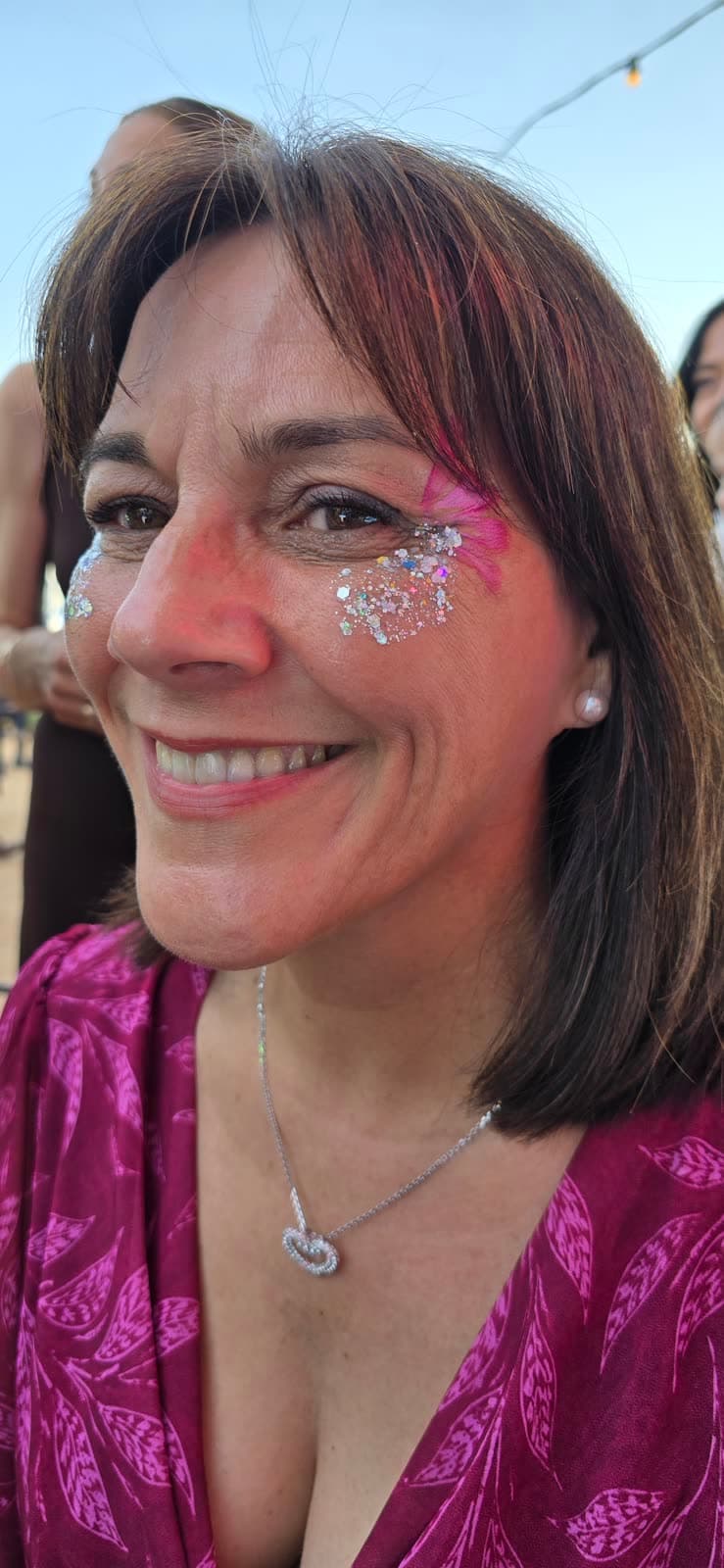 Invitada sonriendo con un maquillaje artístico de glitter en la cara