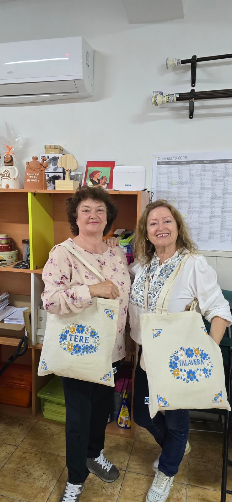 Dos participantes enseñando sus tote bags pintadas en un taller de Butterfly
