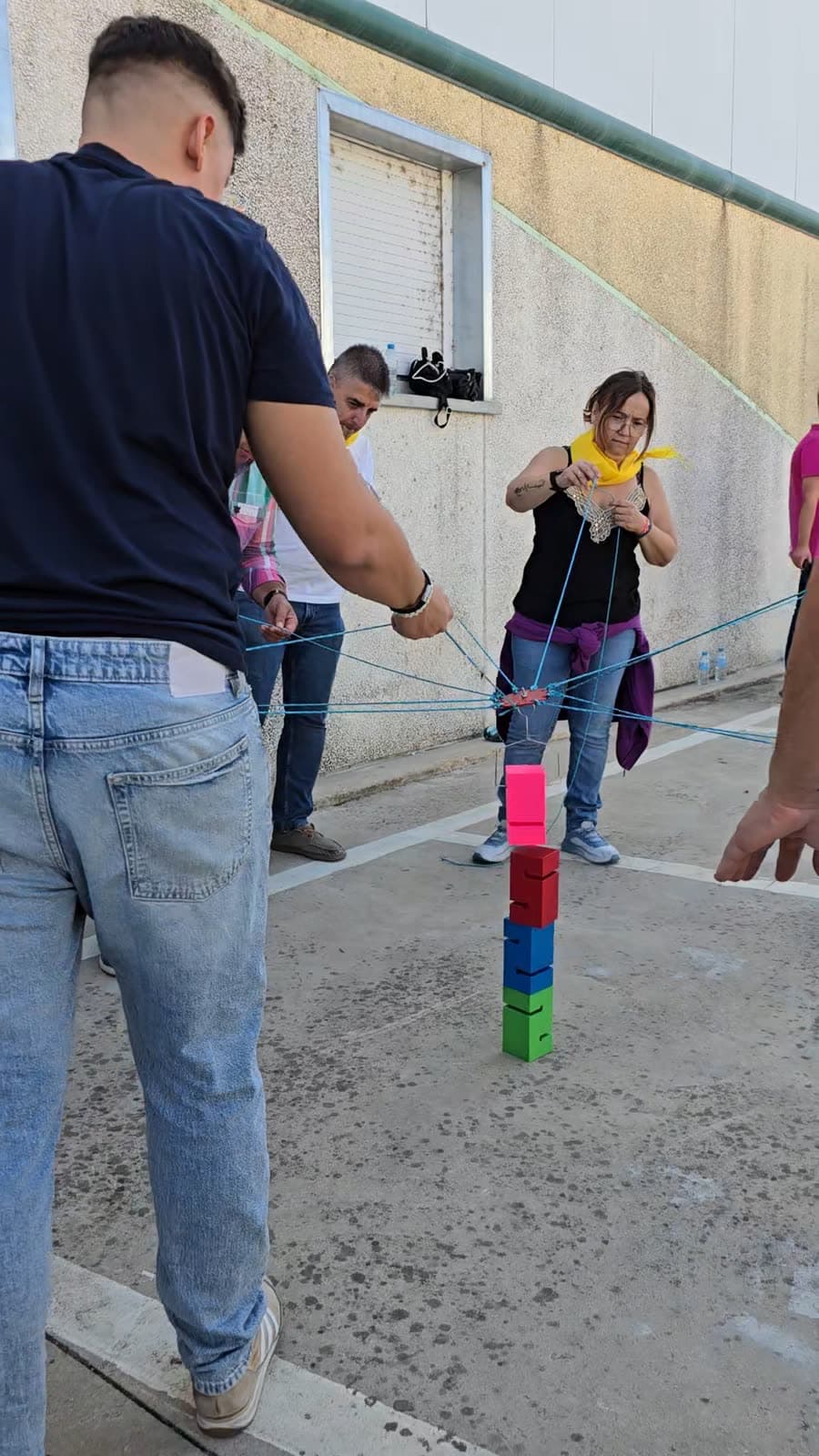 Equipo construyendo una torre de vasos con cuerdas en un team building