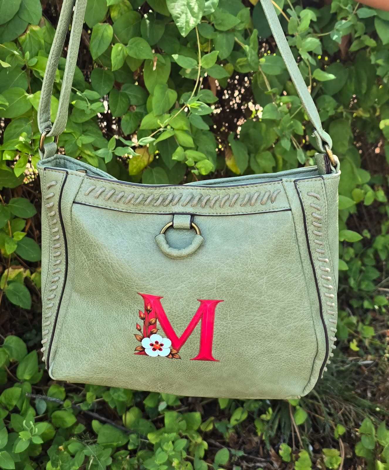 Bolso de polipiel con una M roja y una flor de jara